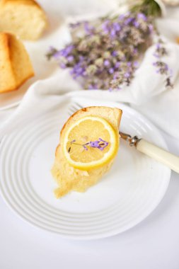 Beyaz masada, lavanta çiçekli bir dilim limonlu kek.