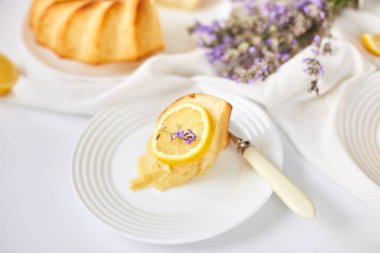Beyaz masada, lavanta çiçekli bir dilim limonlu kek.