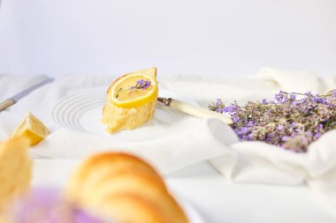 Beyaz masada, lavanta çiçekli bir dilim limonlu kek.