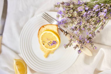 Beyaz masada, lavanta çiçekli bir dilim limonlu kek.