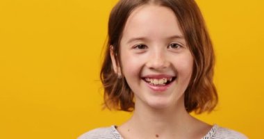 Stüdyonun sarı arka planında mutlu bir genç kız portresi, pozitif duygu yaşam tarzı
