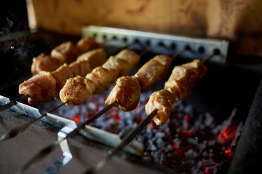 Kebap şişleri, bir evin arka bahçesindeki ızgaranın sıcak kömürlerinin üzerinde pişiyor ve yaz aşçılık geleneğini vurguluyor..