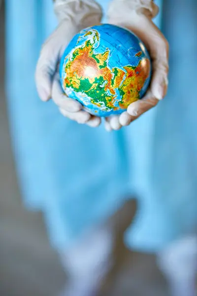 Healthcare worker symbolically cradling the Earth, showcasing care for global health.