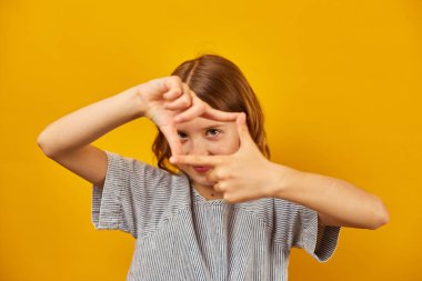 Ergenlik çağındaki bir kız elleriyle bir çerçeve oluşturuyor..