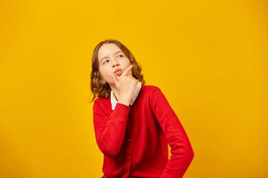 Yüzüne derin düşüncelere dalmış okul üniformalı genç bir kız dokunuyor..