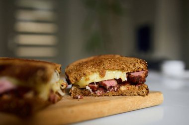 İki kat Reuben sandviçi konserve sığır eti, İsviçre peyniri ve lahana turşusu, ahşap bir tahtaya konmuş, öğle yemeği için mükemmel bir yemek..