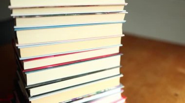 Ahşap bir masanın üzerine düzgünce istiflenmiş renkli kitaplardan oluşan bir derleme. İçlerindeki hikayeleri araştırmaları için bir sıcaklık hissi uyandırıyor ve okuyucuları davet ediyor..