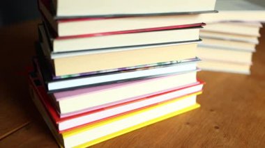 Ahşap bir masanın üzerine düzgünce istiflenmiş renkli kitaplardan oluşan bir derleme. İçlerindeki hikayeleri araştırmaları için bir sıcaklık hissi uyandırıyor ve okuyucuları davet ediyor..