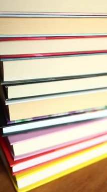 Ahşap bir masanın üzerine düzgünce istiflenmiş renkli kitaplardan oluşan bir derleme. İçlerindeki hikayeleri araştırmaları için bir sıcaklık hissi uyandırıyor ve okuyucuları davet ediyor..