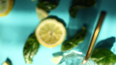 Limon dilimleri, taze fesleğen yaprakları ve buz küpleri parlak mavi bir yüzeye serin ve ferahlatıcı bir yaz atmosferini çağrıştıran içecekler için mükemmel bir şekilde düzenlenmiştir..