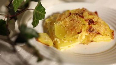 Beyaz bir kırsal mutfak ortamında dilimlenmiş patates ve peynir katmanlarından yapılmış lezzetli rendelenmiş.