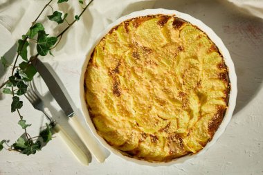 Beyaz bir kırsal masada servis edilen altın kabuklu nefis fırınlanmış graten.