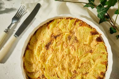 Beyaz bir kırsal masada servis edilen altın kabuklu nefis fırınlanmış graten.