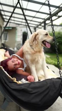 Kızıl saçlı mutlu bir genç kız arka bahçede av köpeğine sarılıyor. Sıcak bir salıncakta birlikte rahatlar, sıcak güneşin ve birlikteliğin tadını çıkarırlar..