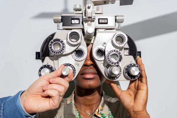 Afrikalı genç bir kız klinikte ya da optik dükkanda göz testi yapıyor. Foropter ekipmanında oturuyor. Göz konsepti