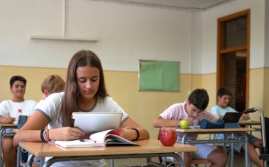 Genç bir kız lise sınıfında dijital tabletle çalışıyor. Okul konseptine dönelim.