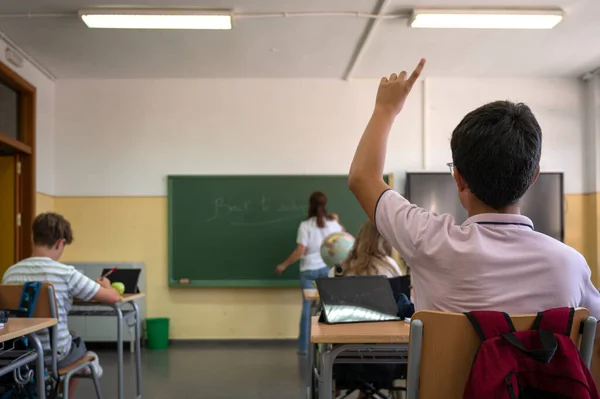 Ένας Έφηβος Σηκώνει Χέρι Του Όπως Γράφει Δάσκαλος Στον Πίνακα — Φωτογραφία Αρχείου