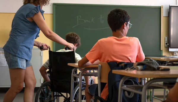 Ένας Δάσκαλος Βοηθάει Έναν Ανάπηρο Μαθητή Μια Αναπηρική Καρέκλα Επιστροφή — Φωτογραφία Αρχείου
