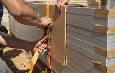 Güneş panellerini turuncu ağ ile bağlayan bir işçinin elleri yakın plan.