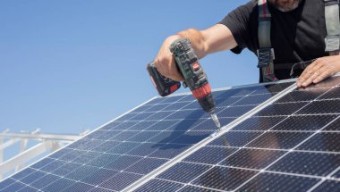 Güneş paneli teknisyeni çatıya güneş panelleri kuruyor. Teknisyen vidalı fotovoltaik mavi güneş modülleri kuruyor. Elektrik paneli güneşi sürdürülebilir kaynaklar