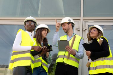 İnşaat alanında güvenlik yelekleri ve başlık takan bir grup işçi.