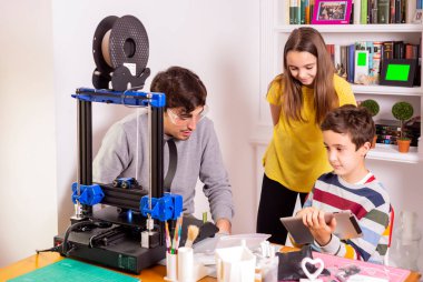 Tabletli bir çocuk öğretmenine bunları 3D yazıcıya yazdırmayı öğretir.