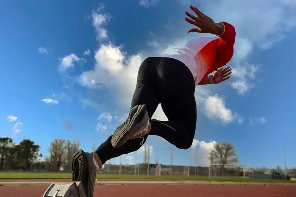 Stock image A young sprinter leaves the starting block at the athletics track.