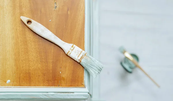 Top view of a used paintbrush on a piece of furniture being restored.