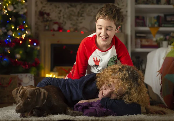 Mom and son lying on the floor with their dog in front of the fireplace at Christmas. Family Christmas concept