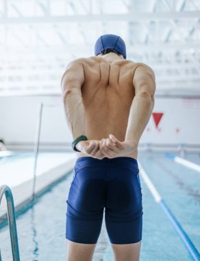 Genç bir yüzücü havuzda antrenmandan önce esniyor. Sağlıklı yaşam ve kendini geliştirme kavramı
