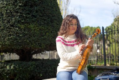 Genç kadın sokakta çalmadan önce keman temizliyor.