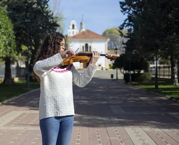 Sokakta keman çalan genç bir kadın müzisyen.