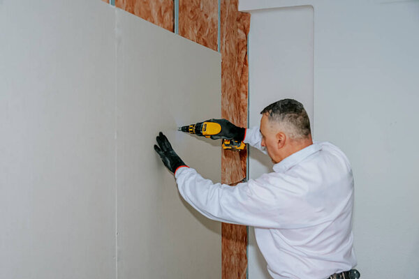 Home renovation. A worker installs plasterboard cladding. Thermal and acoustic insulation of the house.