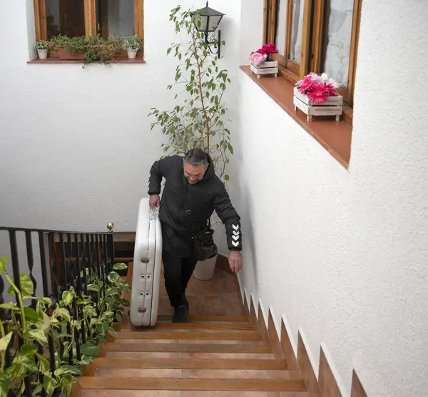 Stock image A physical therapist climbs the stairs of a client's home to perform an in-home massage.