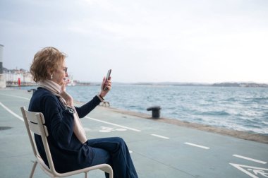 Bulutlu bir günde deniz kenarından arayan yaşlı kadın videosu.