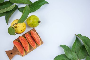 Beyaz arka planda yeşil yapraklı taze guava dilimleri