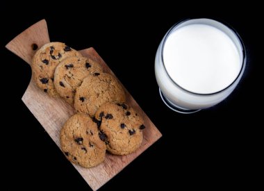 Taze süt ve çikolata parçalı kurabiyeler siyah arkaplanda izole edilmiş.