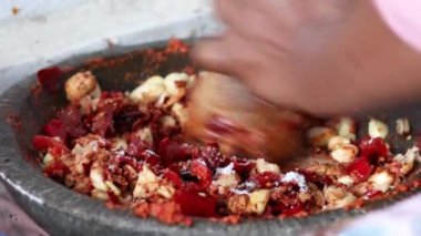 Asyalı kadın baharat öğütmek için geleneksel aletler kullanıyor. Havan ve tokmak.