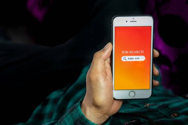 İş Arama Konsepti. Adamın eli akıllı telefonu tutuyor ve iş olanaklarını İnternet 'te iş arama uygulaması kullanarak arıyor.