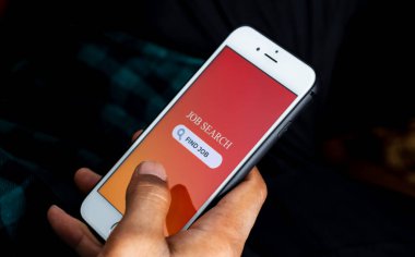 İş Arama Konsepti. Adamın eli akıllı telefonu tutuyor ve iş olanaklarını İnternet 'te iş arama uygulaması kullanarak arıyor
