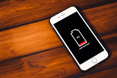 Hücresel Sorunlar ve Enerji Konseptleri. Ahşap arkaplanda düşük pil simgesi olan akıllı telefon.