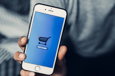 İnternetten alışveriş konsepti. İnternet üzerinden alışveriş yapan bir adamın eli akıllı telefonu tutuyor..