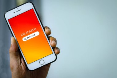 İş Arama Konsepti. Adamın eli akıllı telefonu tutuyor ve iş arama uygulamasını kullanarak iş olanaklarını internette tarıyor.