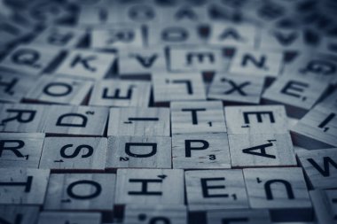 Siyah arkaplana saçılmış alfabe harfli tahta fayanslar.