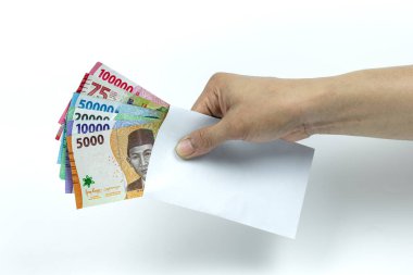 Asyalı bir adamın elinde Rupiah Yığını ya da IDR banknotlarını beyaz arka planda beyaz zarfın içinde tutuyor.