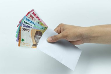 Asyalı bir adamın elinde Rupiah Yığını ya da IDR banknotlarını beyaz arka planda beyaz zarfın içinde tutuyor.