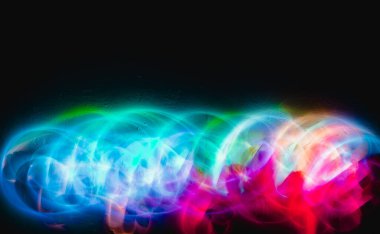 Siyah arkaplan ve duvar dokusunda soyut renkli düzensiz çizgiler. Uzun pozlama. Hafif resim fotoğrafçılığı.