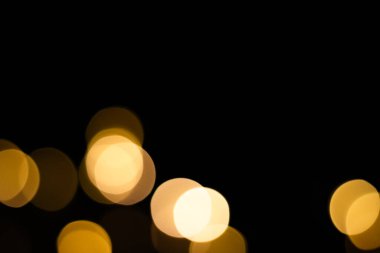 Siyah arka planda bulanık sarı noel ışıkları. Sarı ampuller.