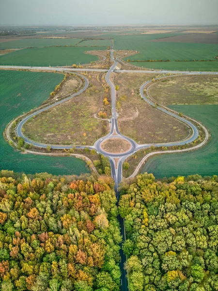 Güzel bir sonbahar ormanında dairesel yol kesişiminde hava manzarası. Sonbaharda yuvarlak kavşağın havadan görünüşü.
