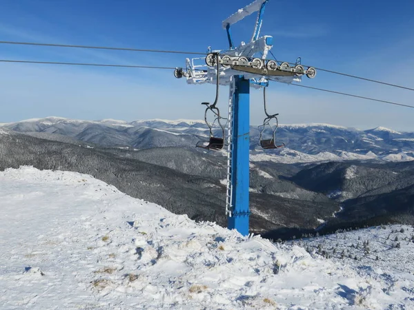 Kışın dağlar, kayak yamaçları ve teleferik, dağlardaki kış ormanlarının arasındaki köy manzarası.